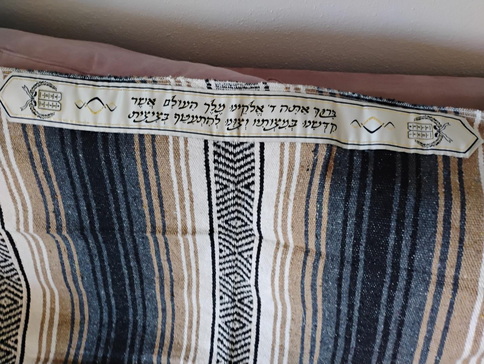 Close-up of the white atarah on the Tierra sarape, embroidered with the wrapping blessing and tablets in wreaths at both pointed ends.